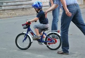 Man holding a child on a bicycle.