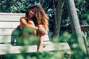 A woman sitting in the sun on a bench.