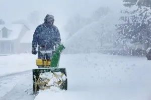 Man cleaning snow with a snow blower.