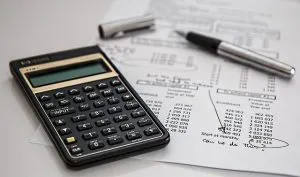 A calculator on a paper and a pen