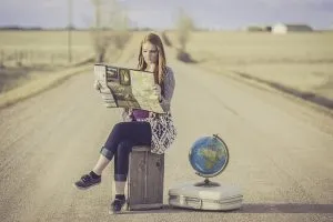A woman with a suitcase, map and a globe ready for international office moving.