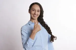 A woman in a blue shirt showing a thumbs up gesture.