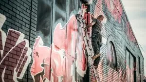 Man drawing graffiti on a wall.