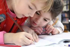 Two girls writing in a notebook.