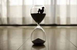 An hour glass with a figure of a man inside, trying to choose international movers on time.