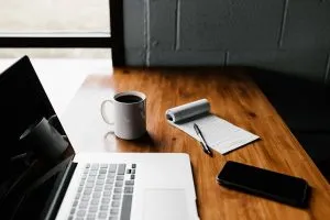 A laptop, a phone and a notebook on a desk