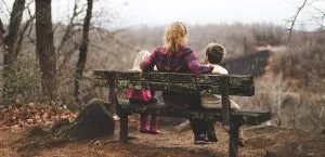 A single mom sitting on a bench with her two kids and talking about relocating as a single parent
