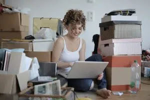 girl on her laptop sitting in a cluttered room