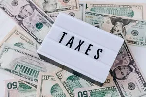 "Taxes" sign on light box, on pile of money