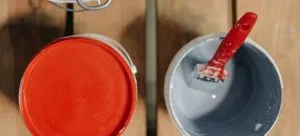 Two cans of paint and a brush inside one of them, a cheap home remodeling idea