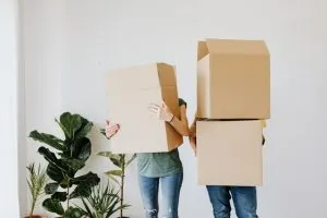 a couple carrying moving boxes