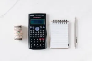 a calculator next to a roll of money