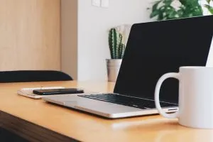 a laptop, a phone and a cup on the desk
