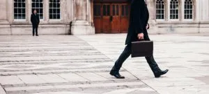man carrying suitcase through the square