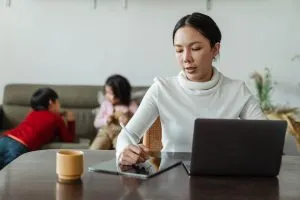 Women in front of the laptop with two kids behind