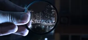 Picture of a person holding a magnifying glass over a city view