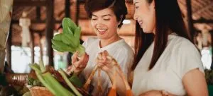two women looking at a piece of vegetable