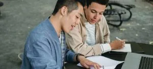 two men writing on papers