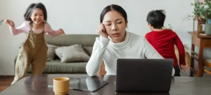 An Asian woman working and kids running around