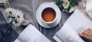 two books and a cup of tea on a grey tablecloth