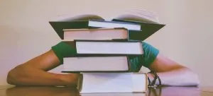 Person with their head behind a wall of books.
