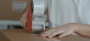 Someone putting tape over a moving box.