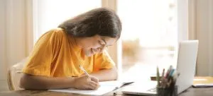 A girl sitting at the table and thinking about moving out while studying.