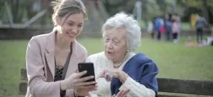 An older lady and her daughter are using their smartphones together