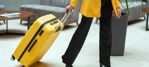 A person in a yellow coat is pulling a suitcase