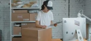 a woman surrounded by boxes and looking at some paperwork
