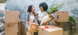 two woman standing surrounded by boxes