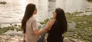 Two women sitting by a lake