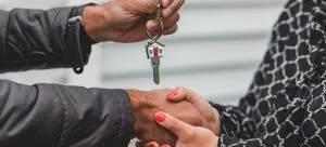 A person handing another person house keys after relocating to the UK