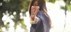 a girl showing peace sign to the camera