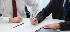 a man in black suit reading a contract before signing it since shady practices to watch out for when hiring movers have become frequent
