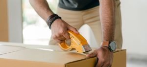 a man sealing the box by taping it