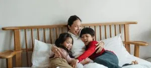 a happy Asian family laying in bed