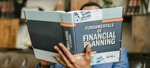 A man holding a book titled "Fundamentals of financial planning"