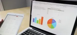 A man holding a tablet in front of a laptop.