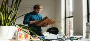 A man standing in an office and holding a box