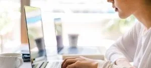 A young woman using a laptop to do good research and prepare, which is one of the tips when moving as a student.
