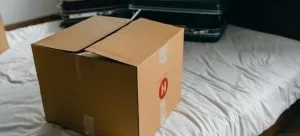 Packing box and suitcases on a bed.
