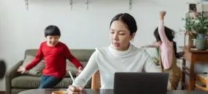 A mom doing research while kids playing in the background. Proper research matters when moving abroad as a single parent.