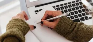 A woman writing down in a notebook and making a plan, which is important when moving with a newborn internationally.
