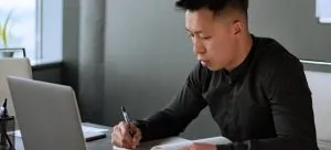 A person writing in a notebook a plan, which is important thing when moving your office locally in Hong Kong.