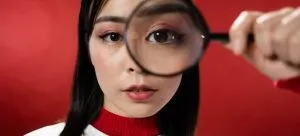 A girl looking thorough magnifying glass.