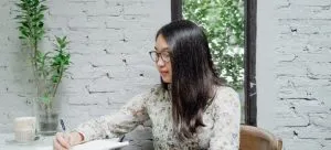 A woman writing in a notebook a timeline which is important when moving from an apartment to a house.