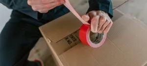 A person using a packing tape to secure a box when moving from Wa Chai to Admiralty.