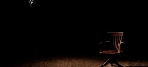An empty brown chair on a theatre stage.